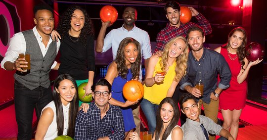 group of friends with drinks and bowling balls