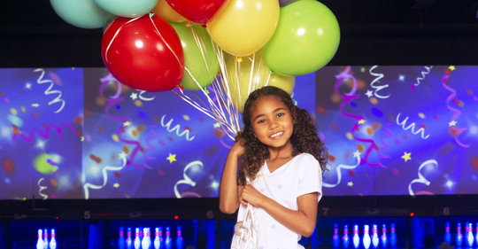 Girl holding a bundle of balloons on the lanes